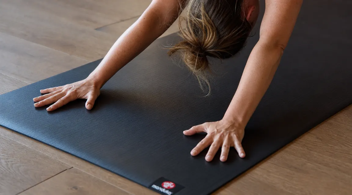 Close-up of hands in downward dog on a new Manduka PRO yoga mat showing the smooth closed-cell surface